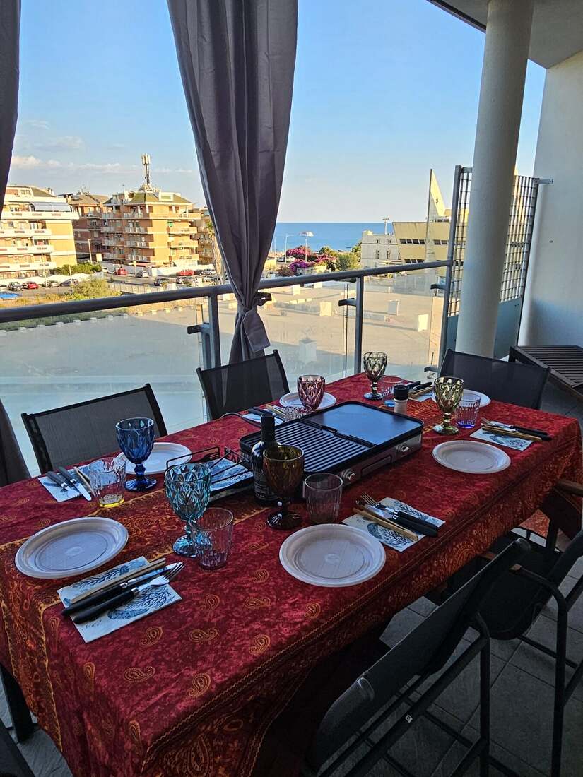 Tavolo apparecchiato sul terrazzo con vista sul mare di Ostia